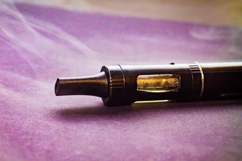 electronic cigarette in a light haze of smoke, vaporizer close on a stand on a purple background