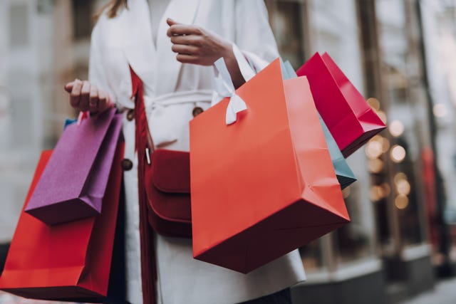elegant young woman with shopping bags standing on the street