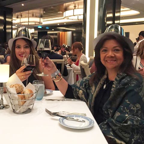 elizabeth and vilma cheersing wearing nye hats and drinking red wine at a restaurant