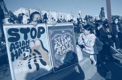 woman holds signs during an anti asian hate vigil the signs read stop asian hate and stop asian hate crimes