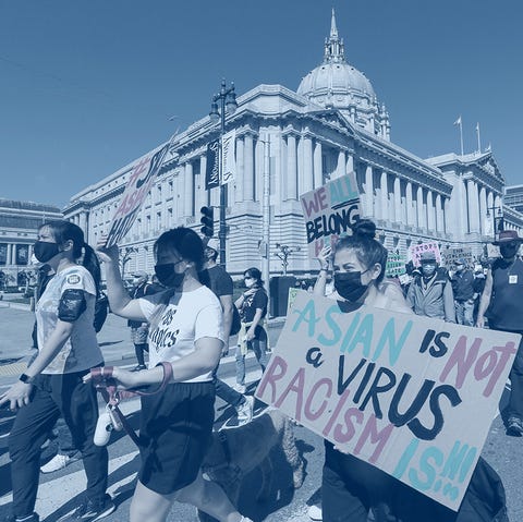 Anti-Asian American hate march and rally demonstrators hold up signs as they take part in an anti asian american hate march and rally the sign reads asian is not a virus racism is