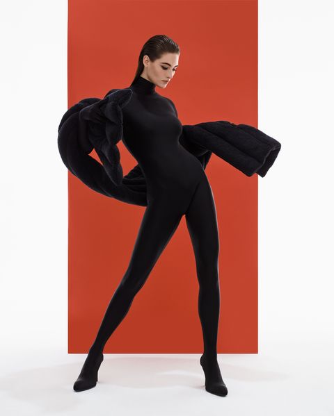model grace elizabeth poses in front of a red well, wearing a black bodysuit, stole and heels