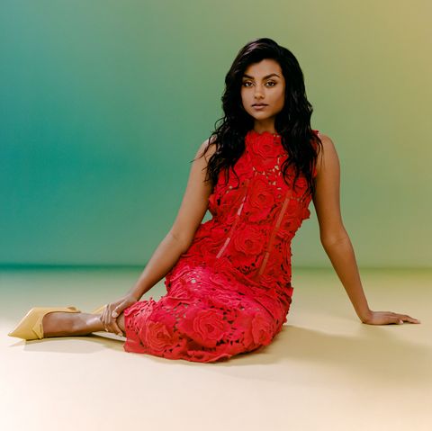 simone ashley poses on the floor in a lace dress and slingback heels
