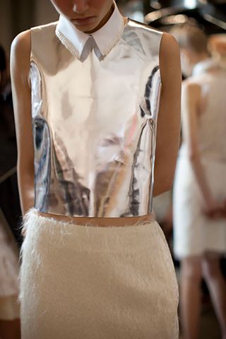 a model in a silver top and white skirt