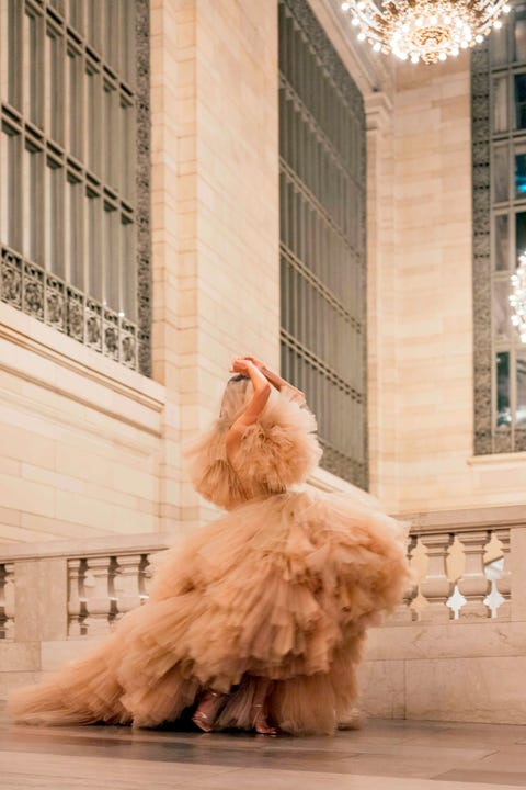 a woman in a pink tulle gown stands on a balcony