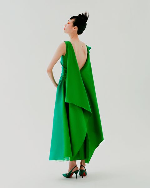 an asian woman in a green backless gown and green shoes
