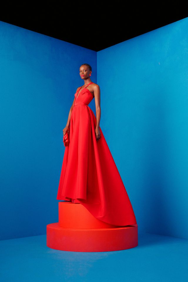 a black woman in a red dress standing on a red pedestal