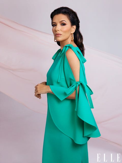 Eva Longoria wears a turquoise dress and stands against a backdrop of light silky fabric eva longoria