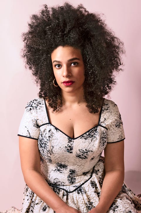 yelaine rodriguez in a white lace dress with black flowers, against a pink backdrop