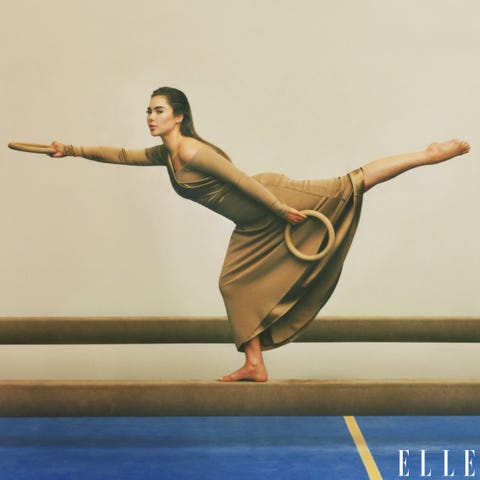 mckayla maroney posing on a balance beam in a beige gown with rings