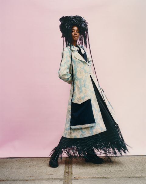 model in pale blue coat and black dress with black headdress