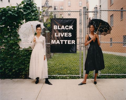 two models with parasols stand next to black lives matter sign in harlem