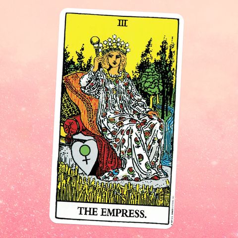 the empress tarot card, showing a female person in a long patterned dress and crown, seated on a throne in the middle of a field