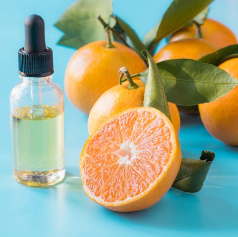 Essential oil of orange mandarin in glass bottle over pastel blue background. Skincare concept.