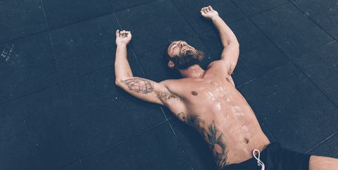 Exhausted male cross trainer lying on gym floor