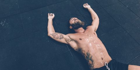 Exhausted male cross trainer lying on gym floor