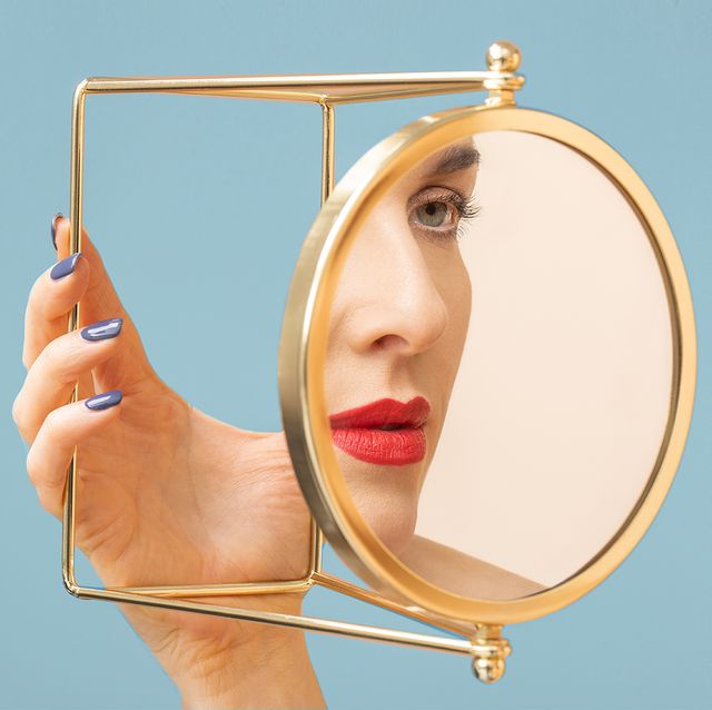 woman looking at face in gold mirror