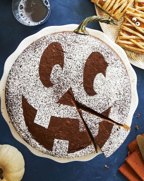 spiced pumpkin molasses cake with a jackolantern pattern on the top in powdered sugar