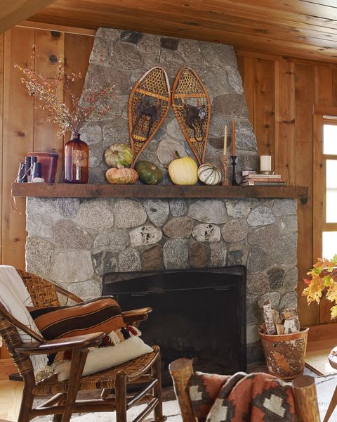 lakeside cabin in cable, wisconsin homeowners nora  o’leary and doug o’leary living room, fireplace, vintage snowshoes, pine walls