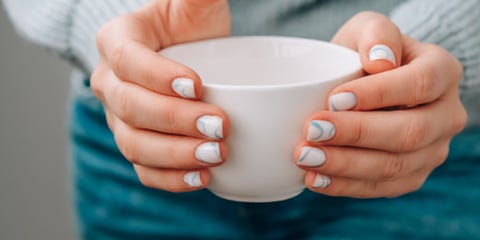 manicured female hands holding white coffee cup with stylish blue nails and minimalistic design trendy modern design manicure gel nails skin care wellness beauty treatment nail care trendy colors beautician advertisement