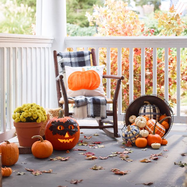fall porch ideas rocking chair surrounded by pumpkins including a carved pumpkin