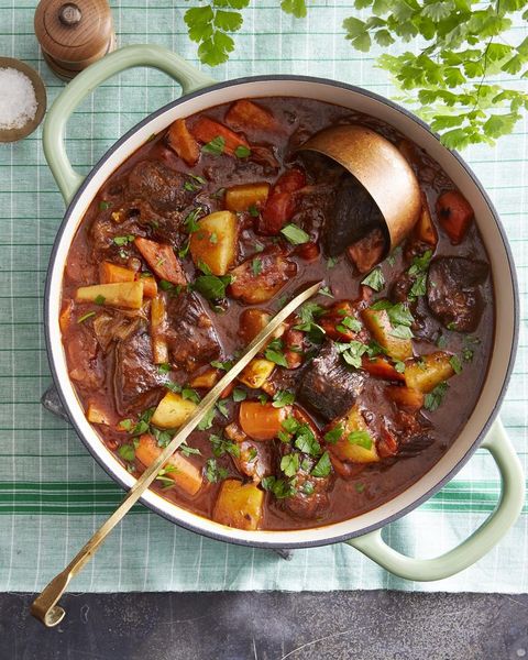 guinness beef stew in a light green dutch oven with a ladle
