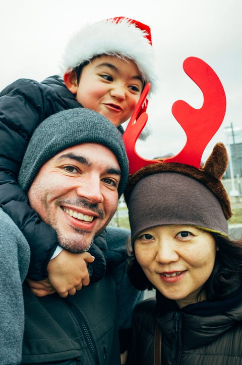 family posing together for a group shot mother and son are wearing christmas hats