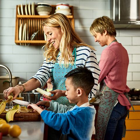cheerful lesbian couple preparing food with adopted son in kitchen, learning, sharing, encouragement