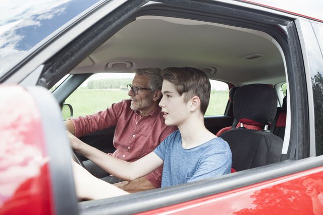 father teaching son driving a car