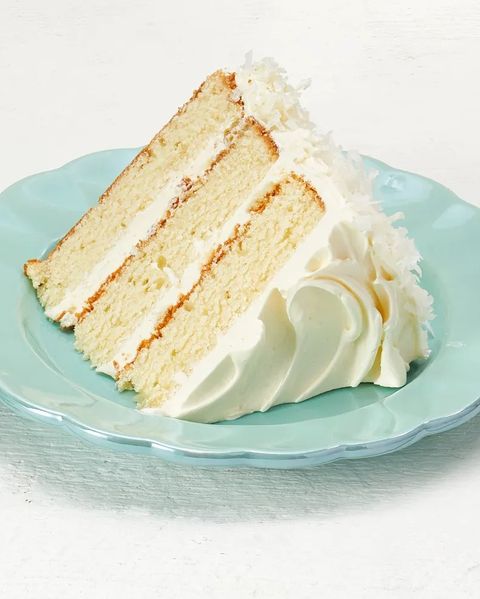 coconut layer cake with white frosting slice on plate