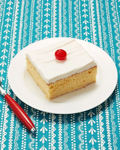 tres leches cake slice on plate with cherry