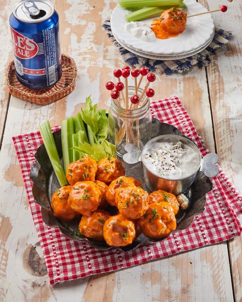blue cheese stuffed buffalo chicken meatballs on a tray with dipping sauce, celery, and skewers for serving