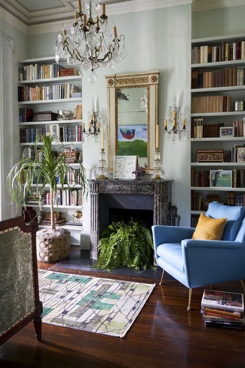 in a small library an existing gilded mirror and fluted mantel mingle with a midcentury armchair