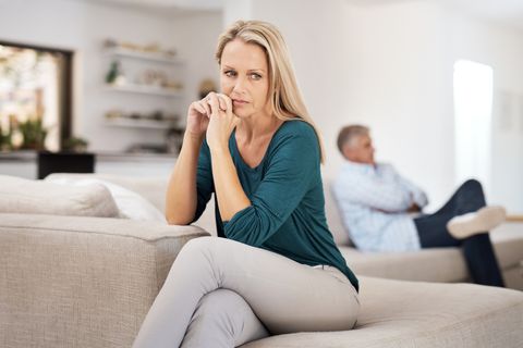 falling out of love woman and man sitting on couch with legs crossed and far away from each other