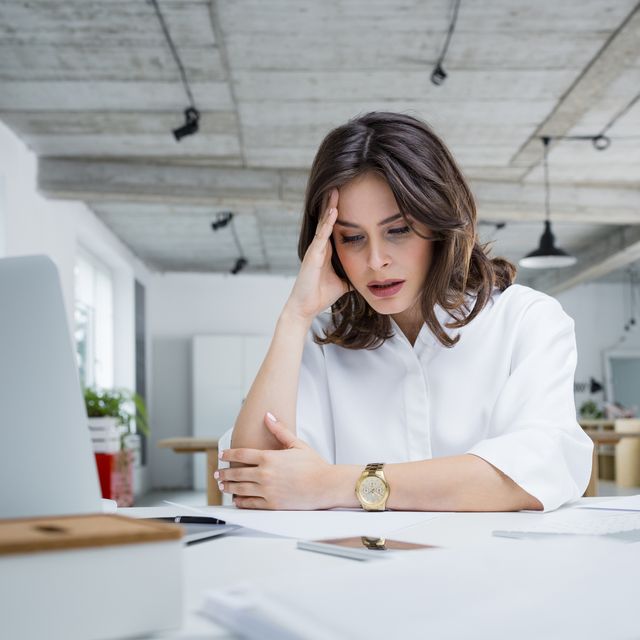 female entrepreneur with headache sitting at desk