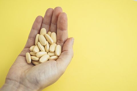 female hand holding some brown pills