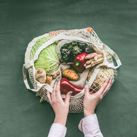 female hands holding eco friendly mesh shopping bag with vegetables