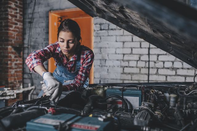female mechanic repairing car engine at garage