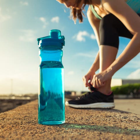 Female runner tying her shoes next to bottle of water
