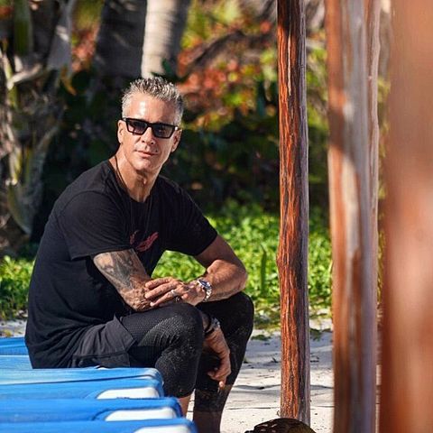 fernando carrillo sentado en una hamaca de playa con camiseta y pantalones negros y gafas de sol