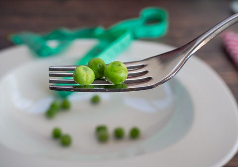 A few peas on a plate and a tape measure. Diet concept