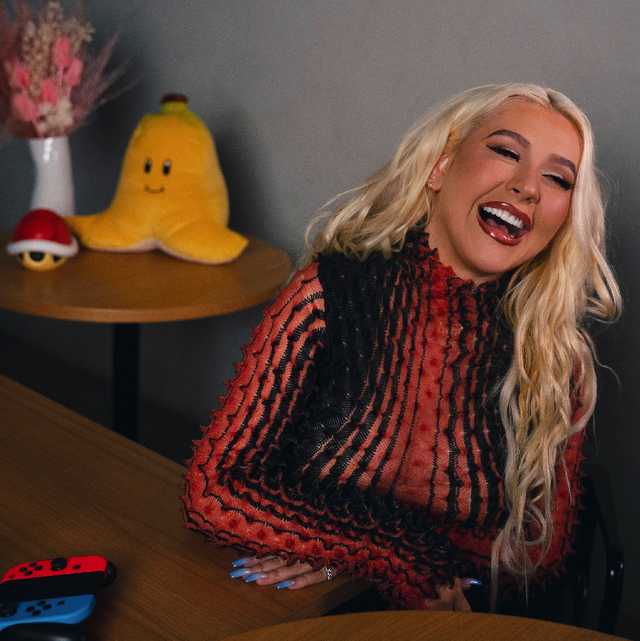 christina aguilera playing mario kart and laughing with a plush banana in the background