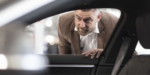 man looking into car in car dealership