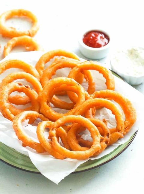 beer battered onion rings on green plate with paper and ketchup in back