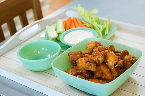 buffalo wings in blue bowl with carrots and celery behind