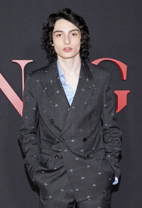 finn wolfhard wears a black suit with a gray pattern on the red carpet