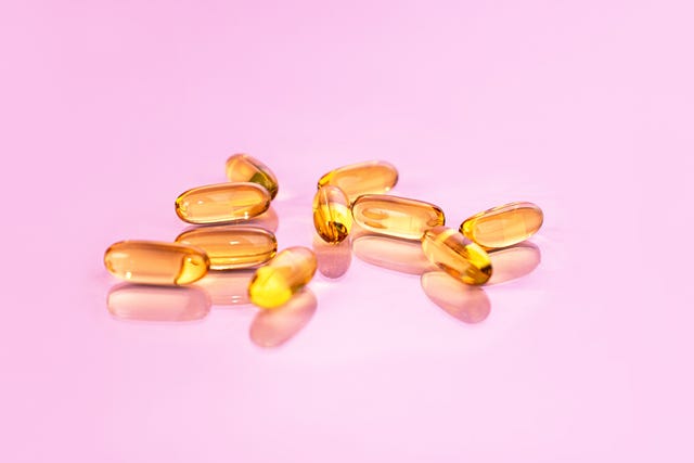 yellow vitamin d supplements on pink background