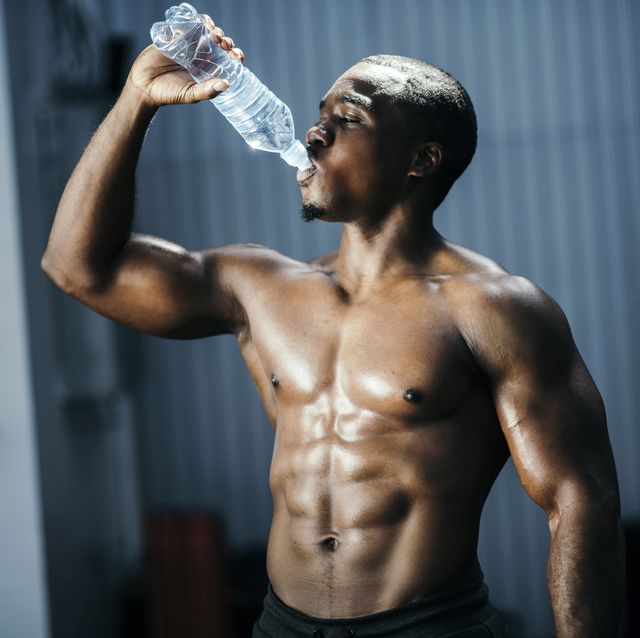 Fit and mascular man drinking water