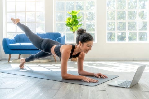 Fit woman doing yoga plank and watching online tutorials on laptop, training in living room fit woman doing yoga plank and watching online tutorials on laptop, training in living room