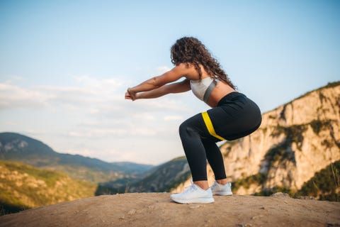 Fit woman squatting on mountain peak Fit woman squatting on mountain peak